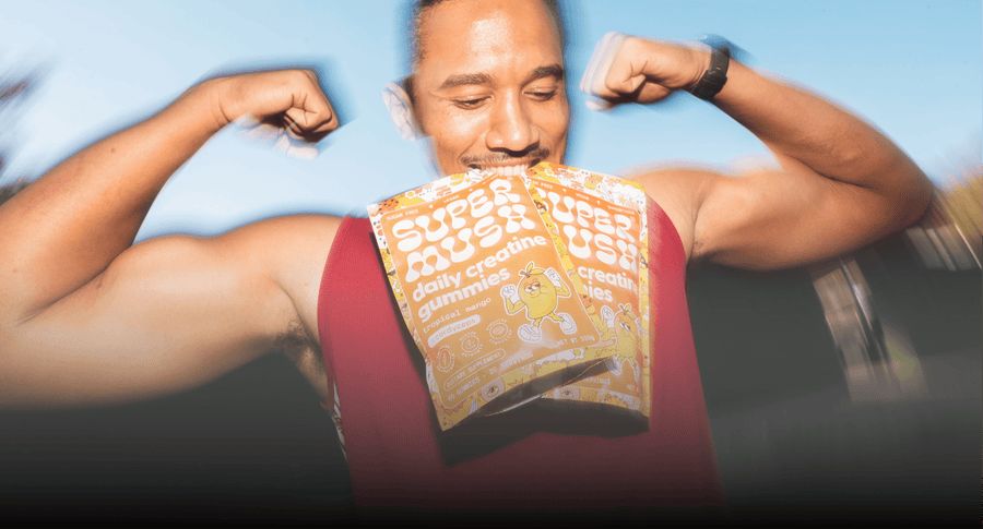 An athlete flexing with two pouches of SuperMush Daily Creatine gummies